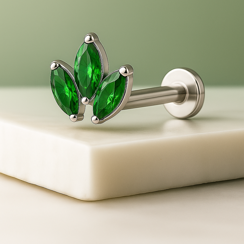 Silver earring with green gemstones on a light beige surface