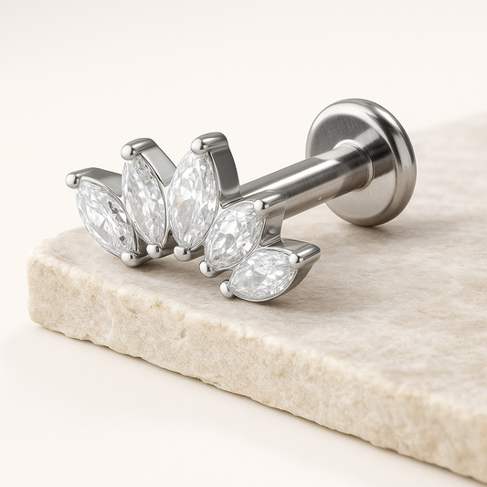 Silver earring with pear-shaped gemstones on a marble surface