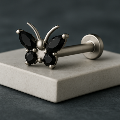 Butterfly-shaped barbell with black gemstones on a gray platform
