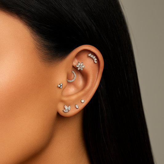 Close-up of an ear with multiple silver earrings against a neutral background