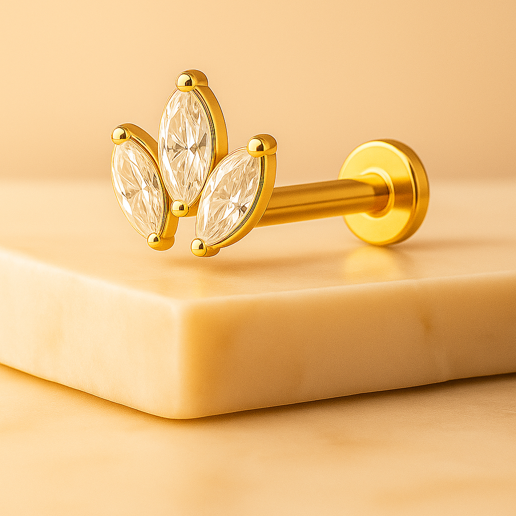 Gold barbell with leaf-shaped crystals on a beige background