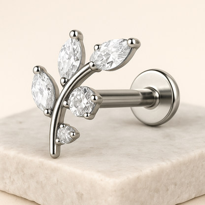 Silver earring with clear gemstones on a beige surface