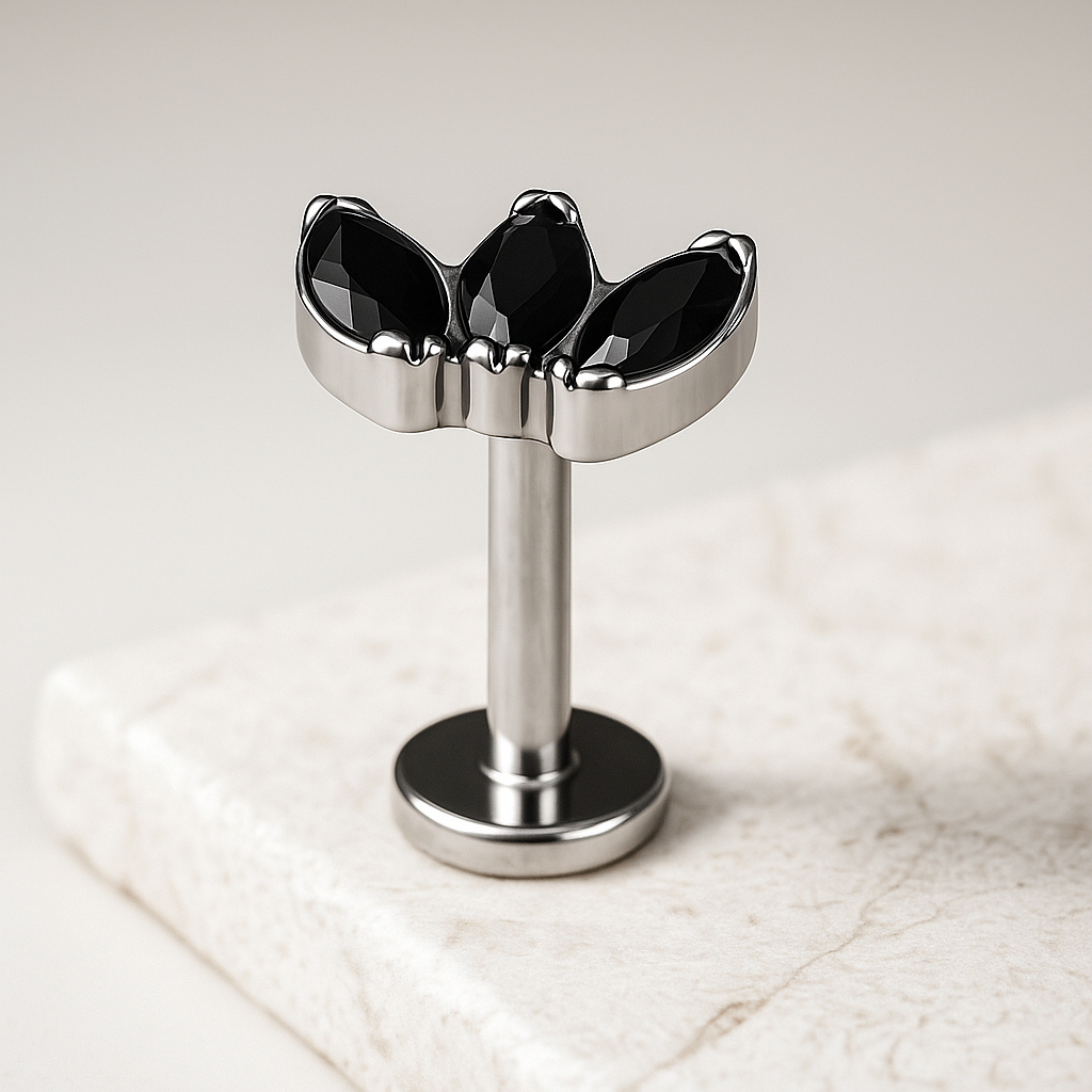 Metallic and black jewelry piece on a light marble background
