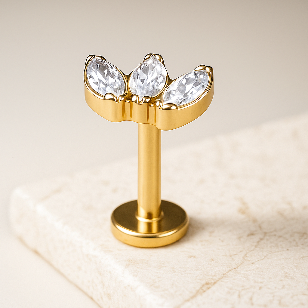 Gold labret with three clear gemstones on a beige background