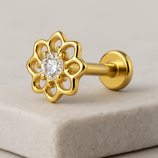 Gold earring with a diamond on a beige stone surface