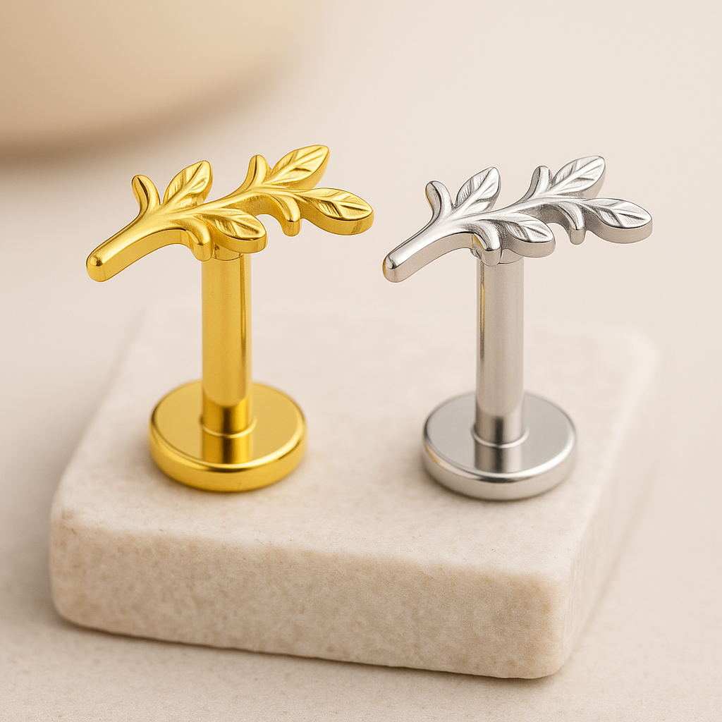 Gold and silver leaf-shaped studs on a beige marble surface