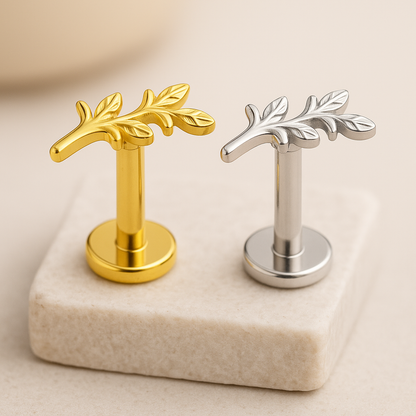 Gold and silver leaf-shaped studs on a beige marble surface