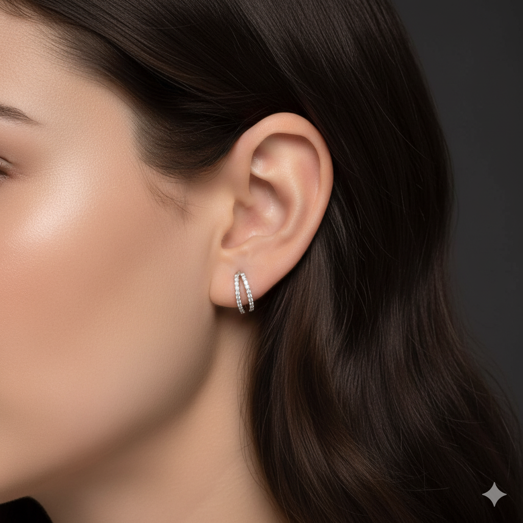 Close-up of an ear wearing a silver hoop earring with a dark background
