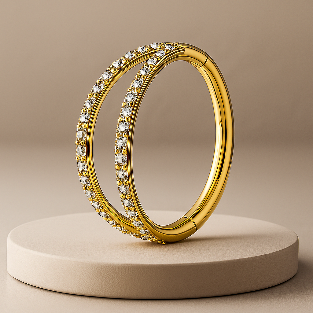 Gold hoop cartilage earring with embedded stones on a beige platform and background