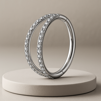 Silver cartilage ring with embedded diamonds on a beige platform