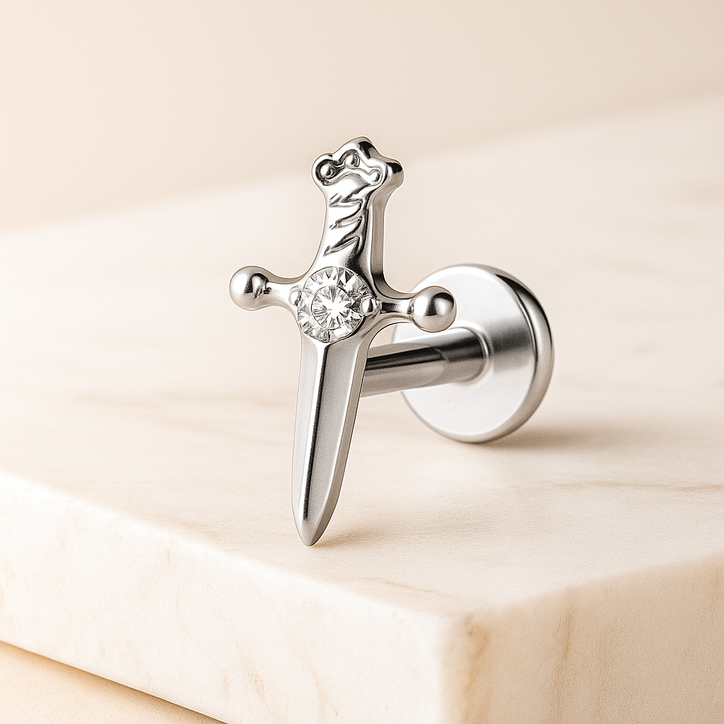 Silver sword earring with a central gemstone on a beige background