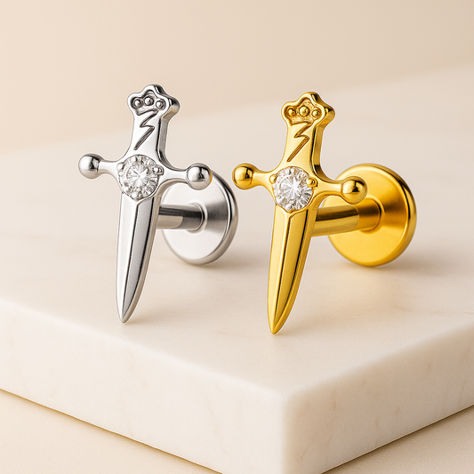 Silver and gold earrings shaped like swords with gemstones on a beige background